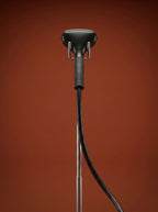 J-4000 Jiffy garment steamer with a black head, silver metal rod, light gray control base, and black cord, displayed on a round red pedestal against a warm rust-orange studio background - Sold by: Best Steamers