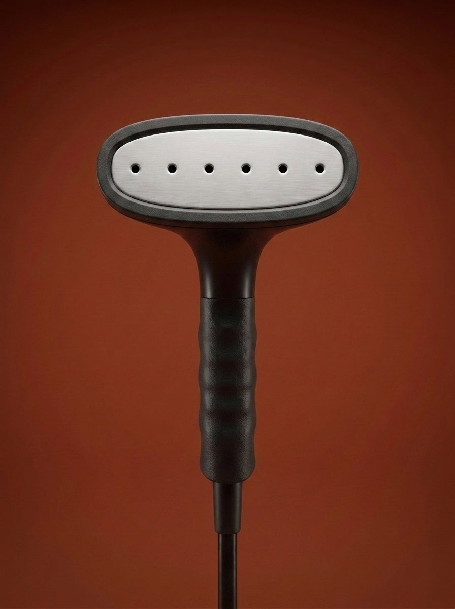 J-4000 Jiffy garment steamer with a black head, silver metal rod, light gray control base, and black cord, displayed on a round red pedestal against a warm rust-orange studio background - Sold by: Best Steamers